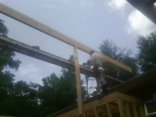 Carpenter setting a ridge beam over a new addition frame — Ice Dam Removal by Roofing Brothers in Wagram