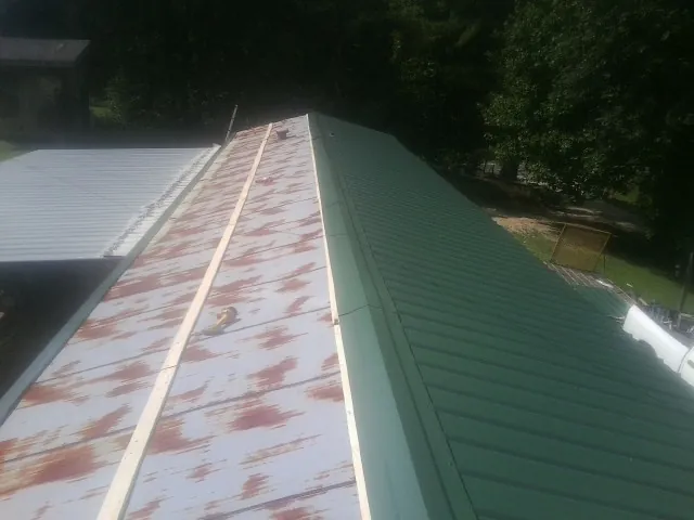 Old rusted panels beside newly installed green metal roofing — Wind Damage Roof Repair by Roofing Brothers in Wagram