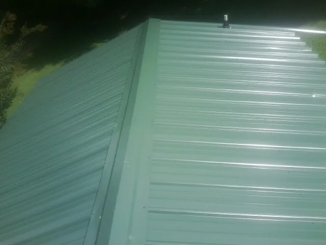 New green metal panels meeting at the ridge of a roof — Flat Roof Repair work by our crew in Wagram