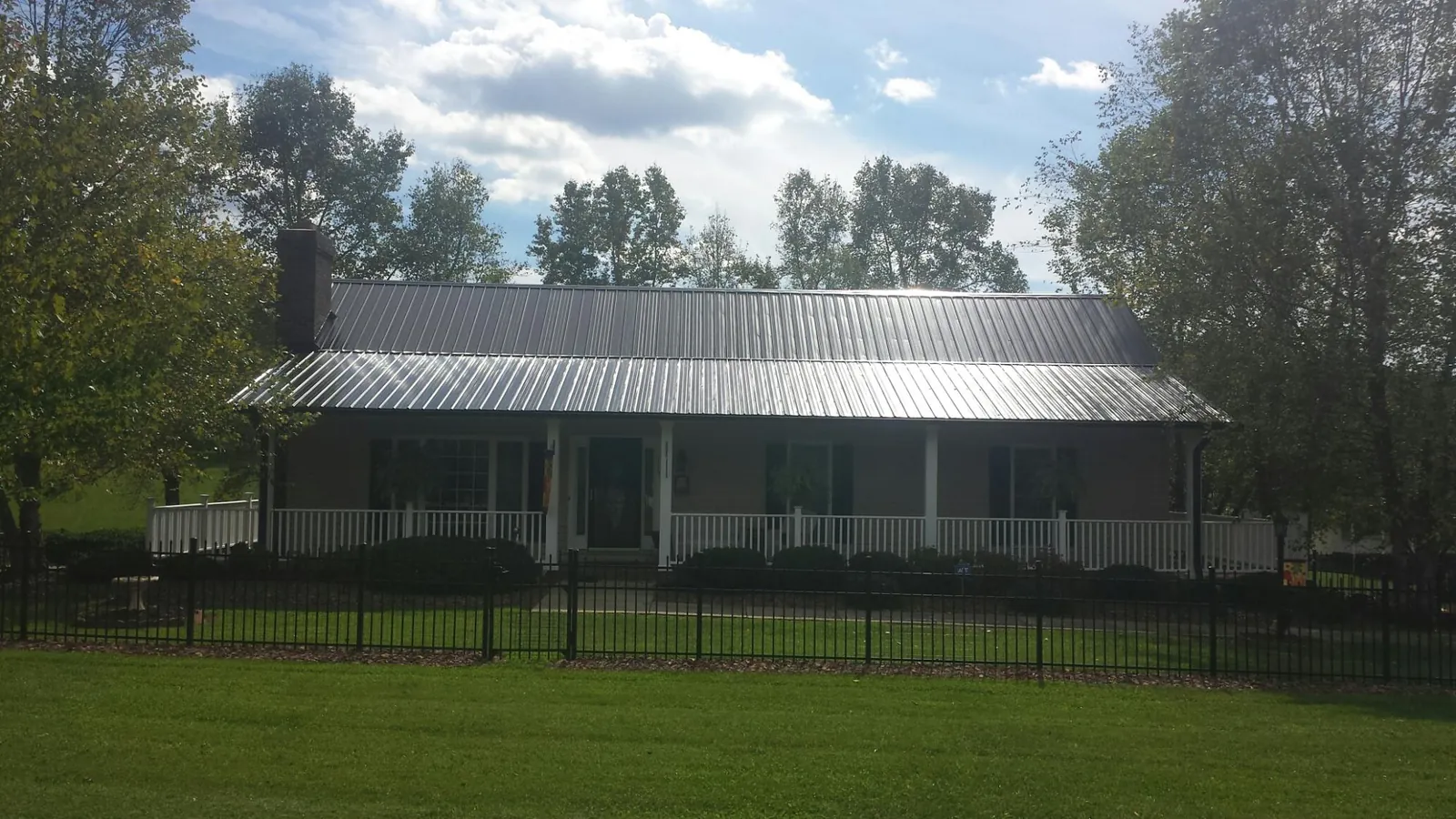 Gray metal roof on a brick ranch with a full width front porch — Gutter Guard Installation work by our crew in Wagram