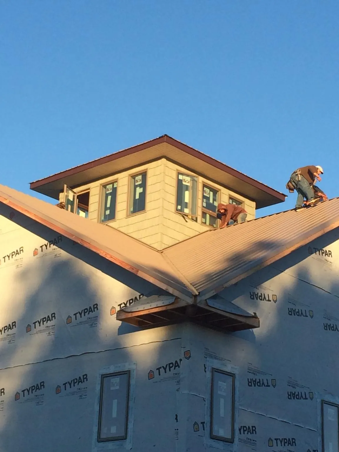 Roofers working around a rooftop cupola on a new metal roof at sunset — Roof Waterproofing in Wagram by Roofing Brothers